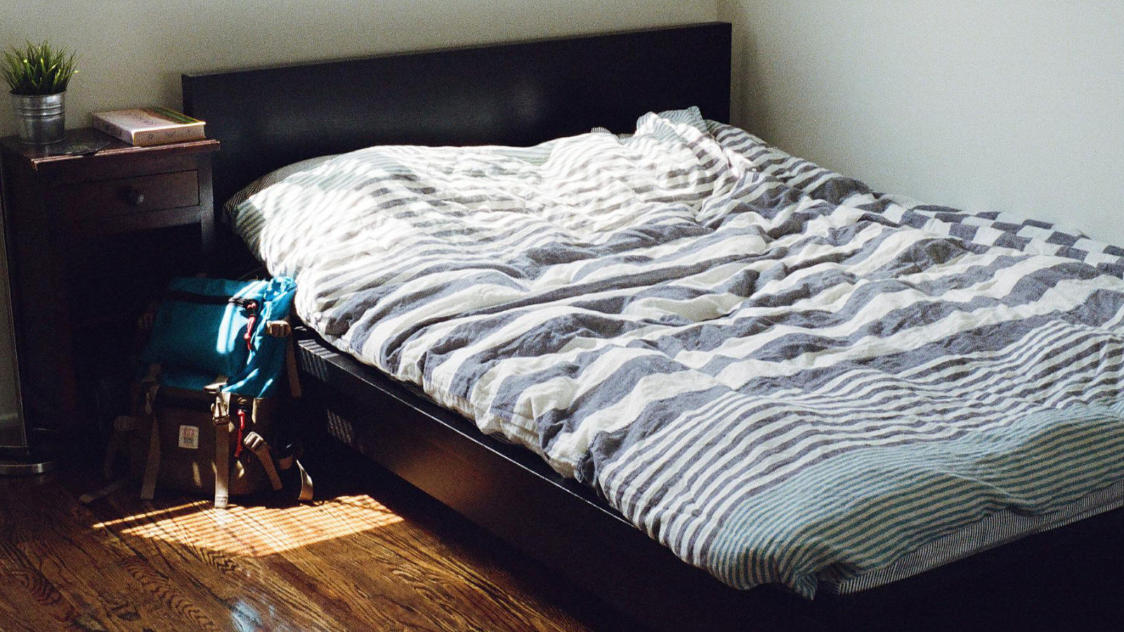 bed with striped bed sheet and a bag on the floor