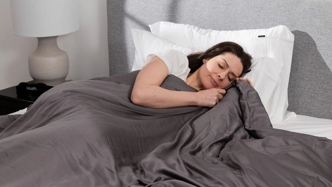 A woman sleeping on the bed while under a Hush Iced Cooling Weighted Blanket.