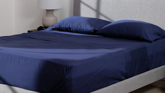 Neatly made bed with Hush Iced Bamboo Cooling Sheets and Pillowcase Set in navy blue color.