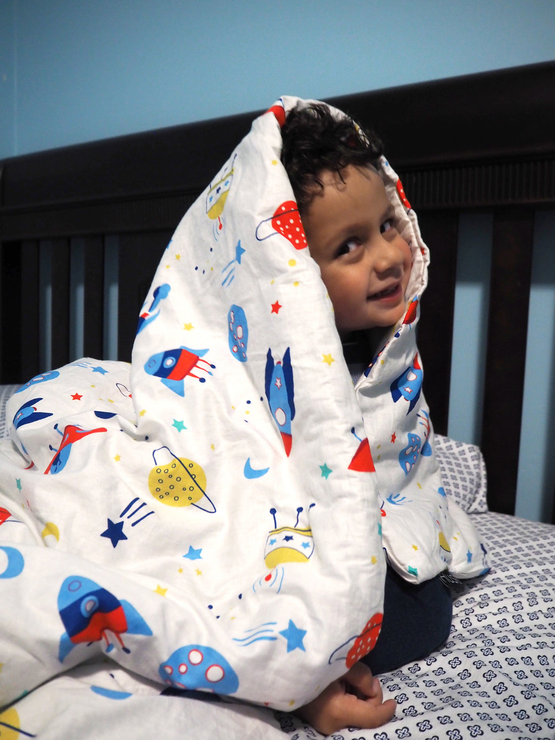 weighted blankets for kids: Child smiling while wrapped in a blanket