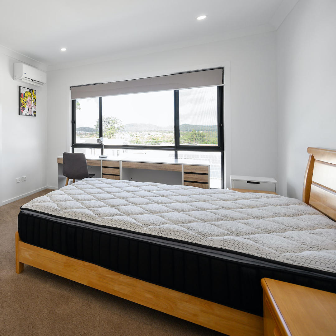 A well-lit bedroom with a new mattress on the bed.