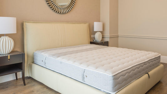 A white mattress on a cream-colored bed frame with two night lamps at each side.