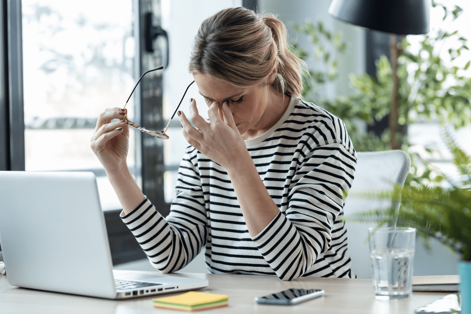 types of stress: stressed woman pinching the bridge of her nose