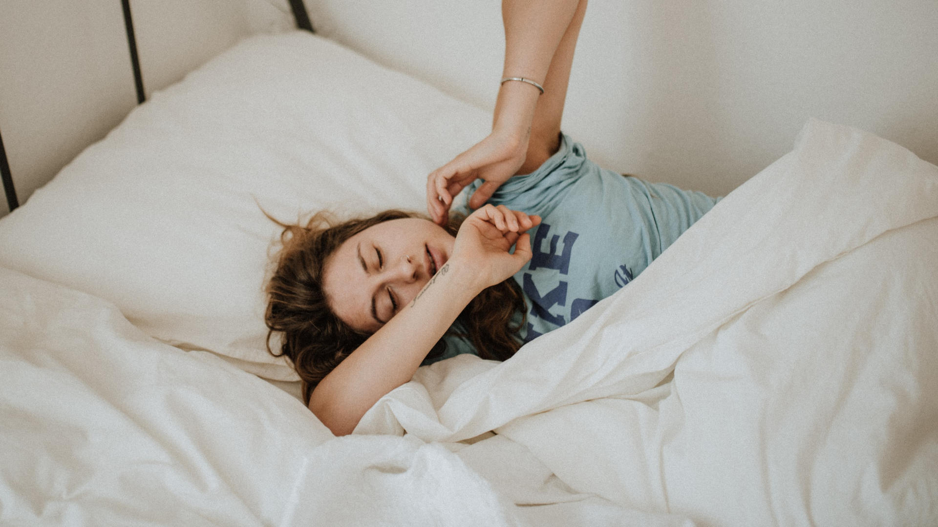 A young woman lying on her bed under a blanket and trying to sleep.