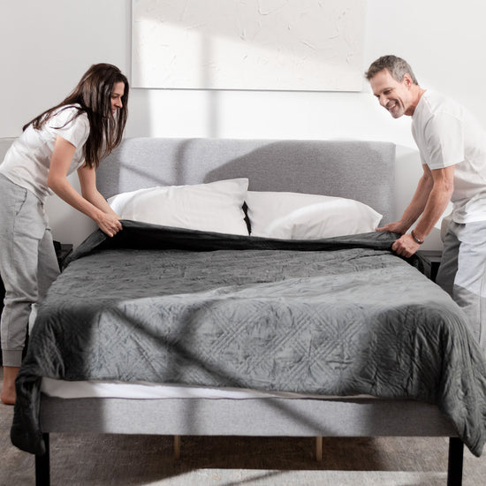 Couple making bed with charcoal weighted blanket