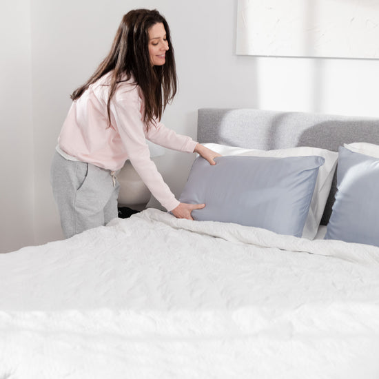 woman making bed with white weighted blanket